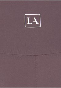 Paarse activewear stof met een klein wit "LA" logo in een vierkant. Glad oppervlak met zichtbare stiksels langs de naden.