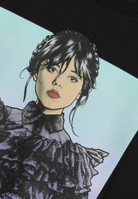 Juodas džemperis su ryškia grafika, kurioje pavaizduota moteris su ilgais tamsiais plaukais, dėvinti pūstą juodą viršutinę dalį ir apykaklę.