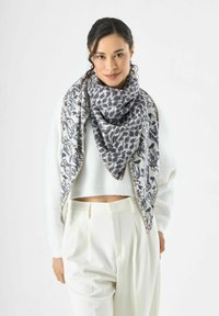 Écharpe texturée présentant un audacieux motif léopard en niveaux de gris avec une bordure illustrée contrastante. Portée en forme triangulaire.