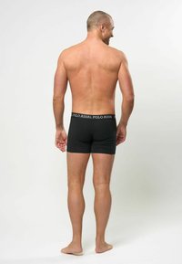 Schwarze Boxershorts aus dehnbarem Stoff mit einem Bund, auf dem von hinten der Schriftzug "POLO ASSN." sichtbar ist. Schlichtes Design, keine Muster.