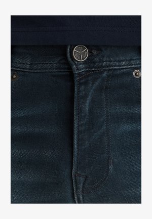 Tmavě modré denimové džíny s klasickým přímým střihem, kovovým zapínáním na knoflík a jemným texturovaným povrchem. Obsahují kontrastní švy a kapsy.