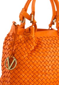 Orange læderhåndtaske med vævet tekstur, glatte detaljer og et rundt metalmærke med "Venezia" præget. Dobbelt håndtag til bæring.