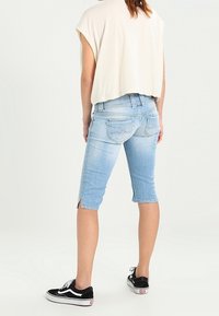 Světlomodré denimové bermudy s vybledlým finišem, délka do kolen, malé postranní rozparky, v kombinaci s černými teniskami. Pohodlný design, bez ozdob.