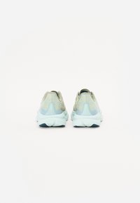 Chaussures de sport légères avec un design beige et bleu texturé, talon rembourré et une épaisse semelle blanche. Support de cheville renforcé.