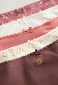 Cinq paires de sous-vêtements féminins en nuances de rose, blanc et marron, ornées de petits nœuds et de motifs floraux ou de rayons de soleil.