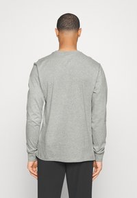 Graues Langarm-T-Shirt aus weicher Baumwolle, mit Rundhalsausschnitt und einem entspannten Schnitt, das eine glatte Textur und ein schlichtes Design bietet.