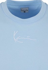 Sweatshirt bleu clair avec un col rond, un col côtelé et un logo blanc brodé. Tissu lisse avec une coupe décontractée.