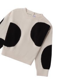 Maglione color crema con grandi motivi circolari neri. Presenta un colletto girocollo e polsini a costine, realizzato in un morbido tessuto testurizzato.