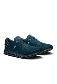 Chaussures de sport bleu marine avec tige en mesh, semelle courbée et accents réfléchissants. Présente un système de laçage et un logo sur le côté.