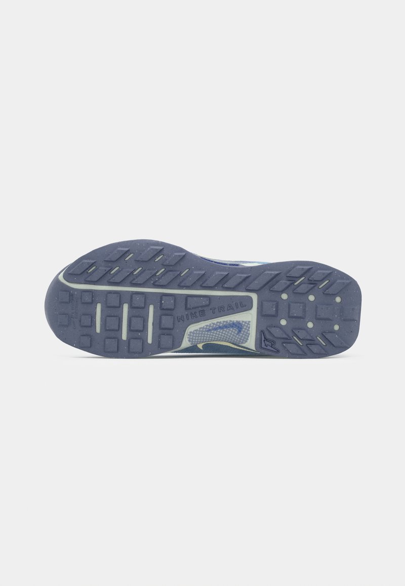 Suela de zapato con ranuras profundas para agarre, etiquetada "Nike Trail", que presenta una mezcla de patrones rectangulares y circulares en goma azul oscura.