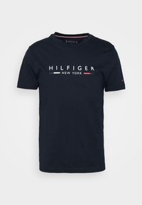 Námořnická modrá bavlněná trička s krátkým rukávem, se bílým textem "HILFIGER NEW YORK" a červenobílými pruhy kolem výstřihu.