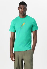 Grøn bomulds T-shirt med rund hals og korte ærmer, der har et grafisk motiv af en malerpensel på brystet. Klassisk pasform.