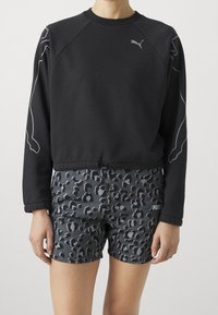 Felpa nera con maniche raglan e dettagli grigi, abbinata a pantaloni corti grigi con stampa leopardata e dettaglio del logo all'orlo.