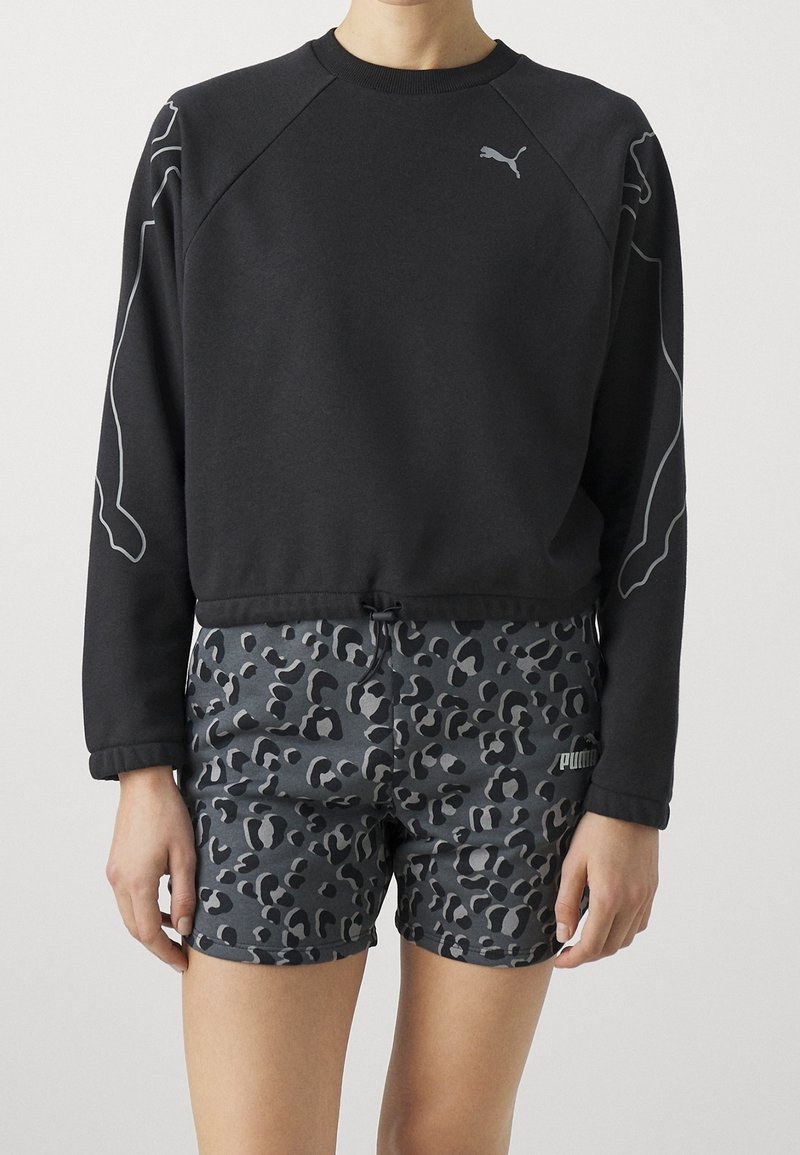Felpa nera con maniche raglan e dettagli grigi, abbinata a pantaloni corti grigi con stampa leopardata e dettaglio del logo all'orlo.