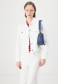 Hvitt denimjakke med sølvfittings, rød og hvit stripegenser under, parret med hvite bukser og en blå håndveske. Glatt tekstur.