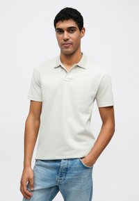 Jasnoszara koszulka polo z dwoma guzikami i kontrastującym kołnierzykiem. Wykonana z miękkiego materiału, posiada krótkie rękawy i subtelne logo.