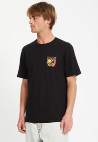Sort bomulds t-shirt med rund hals, der har et farverigt kranie- og blomstertryk på venstre brystområde. Korte ærmer, afslappet pasform.