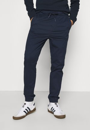Marineblauwe joggingsbroek gemaakt van lichtgewicht stof, met een elastische tailleband met trekkoord, omgeknoopte enkels en zijzakken.