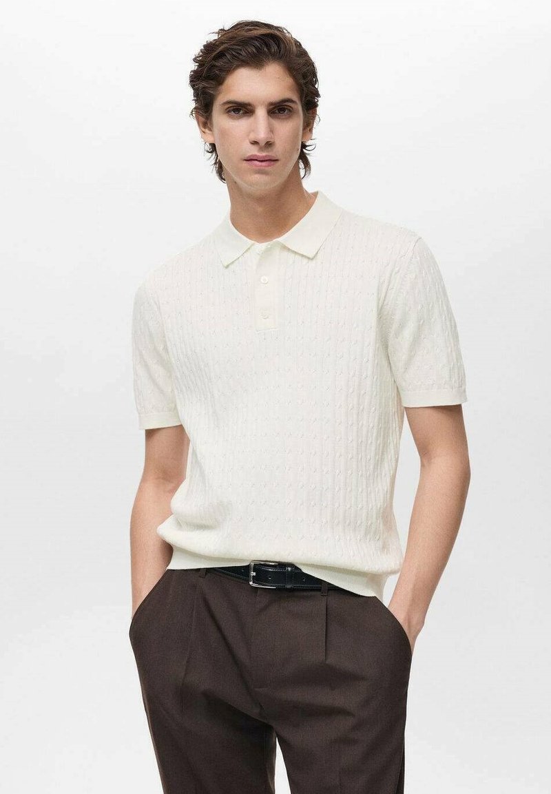 Short-sleeve cream polo shirt with textured design and a classic collar, paired with dark trousers and a black belt.