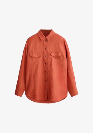 Chemise orange rouille à manches longues, boutonnée avec col pointu et deux poches poitrine à rabats, présentée à plat sur fond blanc.