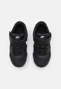 Mustat Nike-tennarit, joissa on verkkomateriaali ja synteettinen päällinen, varustettuna tarranauhalla, nauhoilla, valkoisella swoosh-koristeella ja valkoisella pohjalla.