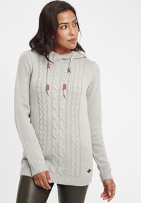 Hellgrauer Strickpullover mit einem Zopfmuster, Kapuze und verstellbaren Kordelzügen. Akzentuiert mit einem kleinen braunen Leder-Logo-Patch.