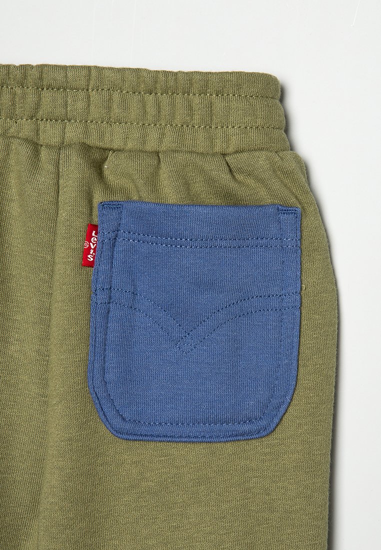 Pantaloni tuta verde oliva con una tasca a pattina blu. Caratterizzati da una vita elastica, una texture morbida e dettagli di cucitura in contrasto. Etichetta di brand Levi's visibile.