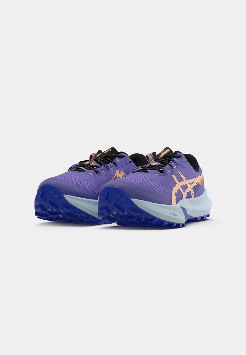 Lila löparskor med svarta accenter och orange logotyp. Texturerad ovandel, dämpad sula med blått grepp på yttersulan för stabilitet.