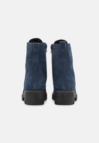 Stivaletti ankle in suede blu navy con punta rotonda, suola in gomma nera e cerniere laterali, caratterizzati da dettagli di cucitura verticale lungo i lati.