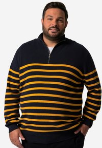 Svetr s modro-žlutými pruhy a límcem na polo-zip. Hladký strukturovaný vzor, dlouhé rukávy a volný střih. Tmavě modrá základní barva s výraznými žlutými pruhy.