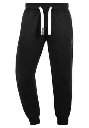 Schwarze Sweatpants mit einem Kordelzugbund, weißen Akzenten, zwei Fronttaschen, gerippten Bündchen und einem Logo an der Seite. Hergestellt aus weichem Baumwollmaterial.