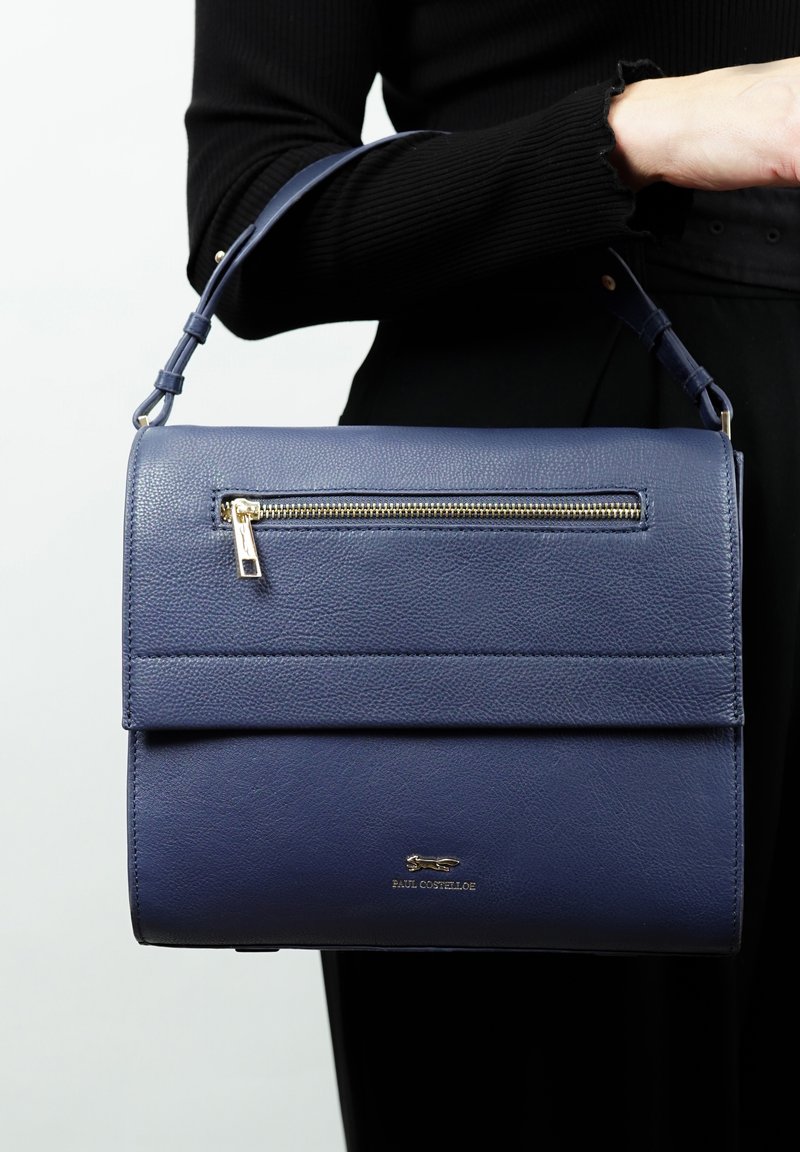 Donkerblauwe textuur leren handtas met een bovenhandvat, een voorzak met rits en gouden hardwareaccenten. Glad oppervlak met een modern, gestructureerd ontwerp.