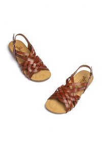 Sandalias de cuero marrón con tiras trenzadas, punta abierta y una correa ajustable en el tobillo, que cuentan con una suave plantilla de ante color marrón claro.