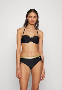 Juodas bikini, kurio viršus be petnešėlių su auksuotu akcentuotu dirželiu ir atitinkamos kelnaitės su auksine juosmens juostele bei šoninėmis surišimo detalėmis.