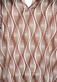 Tessuto marrone con motivi geometrici verticali a onde bianche che somigliano a filamenti di DNA, caratterizzato da punti e linee in un design ripetitivo.