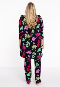 Ensemble de vêtements d'intérieur à imprimé floral noir, comportant de grandes fleurs roses, violettes et vertes. Comprend un haut à manches longues et un pantalon ample.