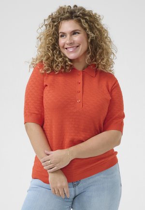 Oranje polo trui met korte mouwen, voorzien van een gestructureerd patroon, drie-knoopsluiting en geribde manchetten, gecombineerd met lichtblauwe jeans.