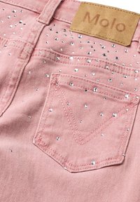 Ružová denímová látka s bočnou kapsou zdobenou malými striebornými kamienkami a béžovou prešívanou značkovou nálepkou s nápisom "Molo."