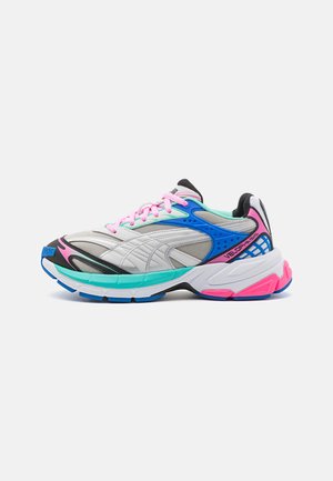 Chaussures de course avec une tige en mesh argentée, bleue et rose. Elles disposent d'une semelle épaisse avec une finition texturée et des couleurs contrastantes.