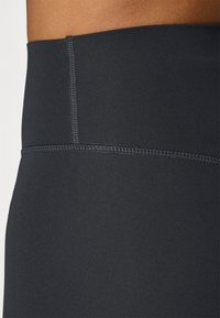 Black high-waisted leggings with a smooth, stretchy fabric. Features flatlock seams for comfort and a subtle waistband design.