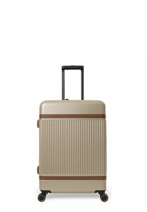Kovahtelainen beige matkalaukku, jossa pystysuorat uritukset, ruskea reunus, pidennetty musta teleskooppikahva ja neljä pyörivää pyörää valkoisella taustalla.