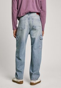Pantalones cargo de mezclilla azul claro con un corte relajado, que cuentan con dos bolsillos laterales, dos bolsillos traseros y detalles de costura visibles.