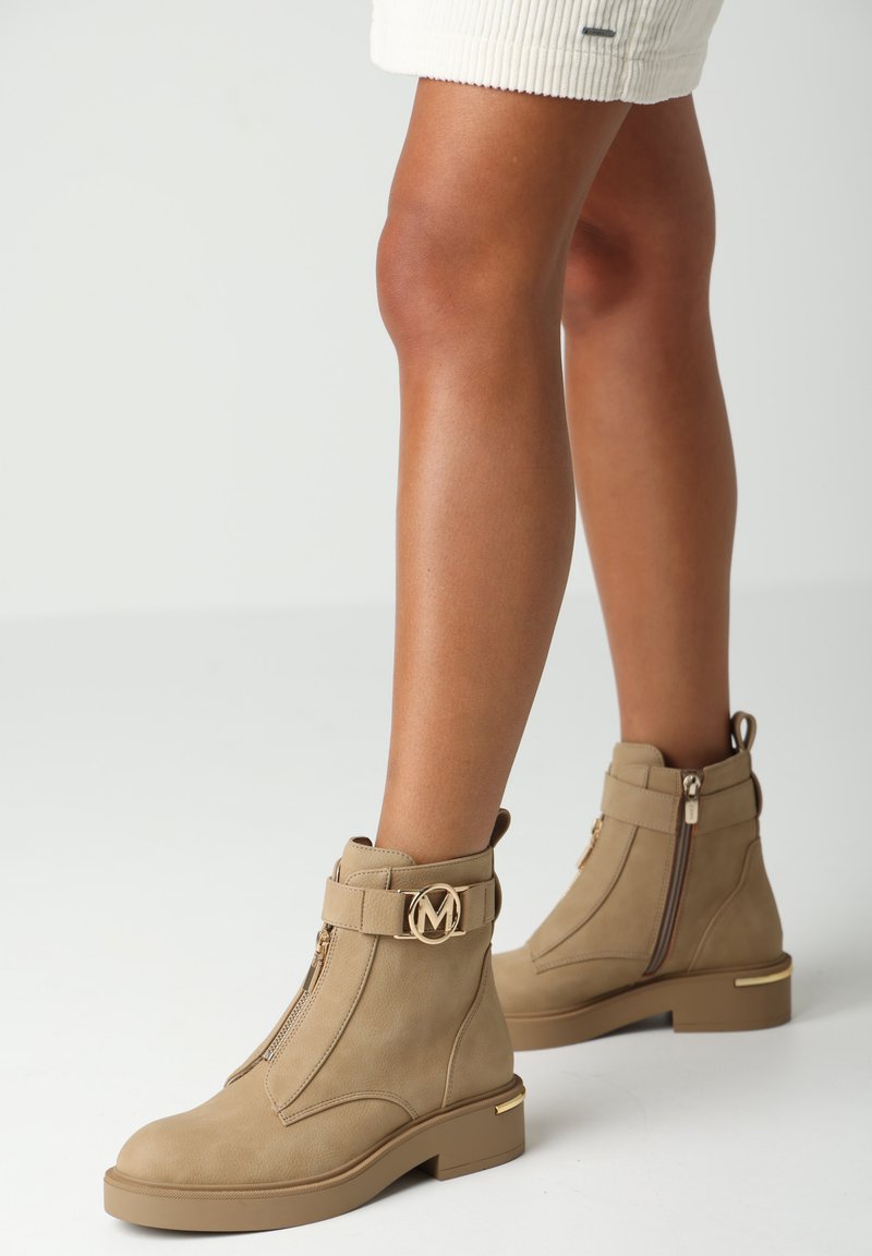 Kahové kotníkové boty vyrobené z hladké kůže, s zlatým logo detailem, bočním zipem a blokovým podpatkem. Pevný design s minimalistickým stylem.