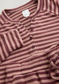 Bluza cu mânecă lungă, cu dungi în nuanțe de roz prăfuit și burgund, având o deschidere cu nasturi, decolteu rotund și un buzunar pe mâneca stângă.