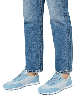 Sneaker azzurri chiari con design in materiali misti, caratterizzati da superfici lisce e texture, lacci e suole bianche.