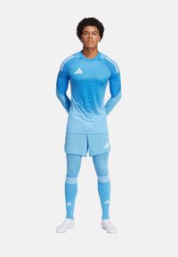 Kit da calcio azzurro chiaro con un design a gradiente, maniche lunghe, tre strisce bianche sulle spalle, pantaloni corti coordinati, calze lunghe e scarpini.