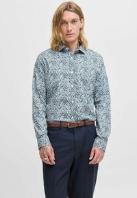 Camicia button-up con stampa floreale blu, maniche lunghe, in cotone, colletto, abbinata a pantaloni blu navy e una cintura in pelle marrone.