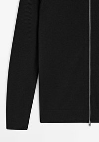 Maglione nero con zip, texture a coste, maniche lunghe e cerniera argentata. Design moderno con silhouette aderente.