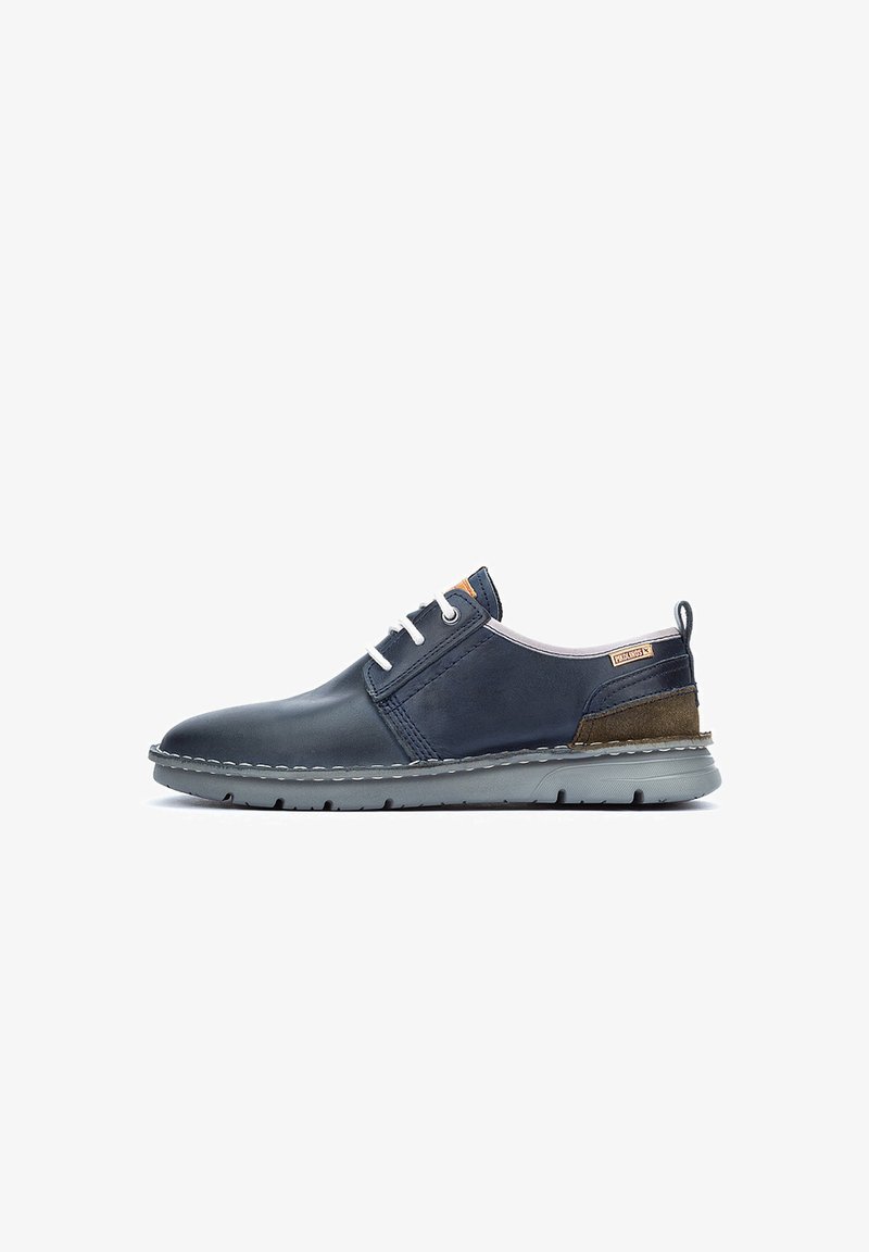 Marine lederen schoen met grijze rubberen zool, witte veters en een bruine suede accent bij de hak. Heeft gestikt detail en een logo label.