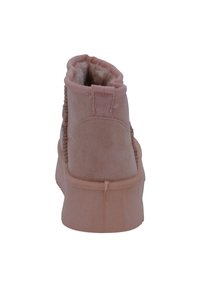 Stivale alla caviglia in suede rosa con morbida foderatura in pelliccia, cuciture laterali testurizzate e un anello sul tallone per facilitarne l'indossamento.